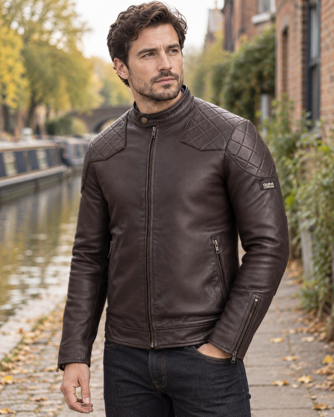Male model wearing the brown QUIVE London BROMPTON leather biker jacket beside a softly blurred English canal in autumn