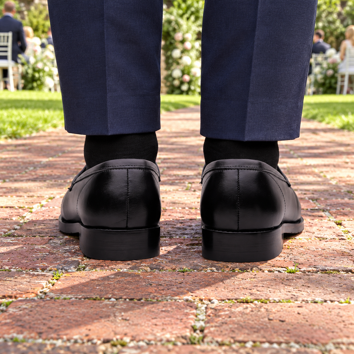 Rear view of ALBANY black calf leather penny loafers at a garden wedding
