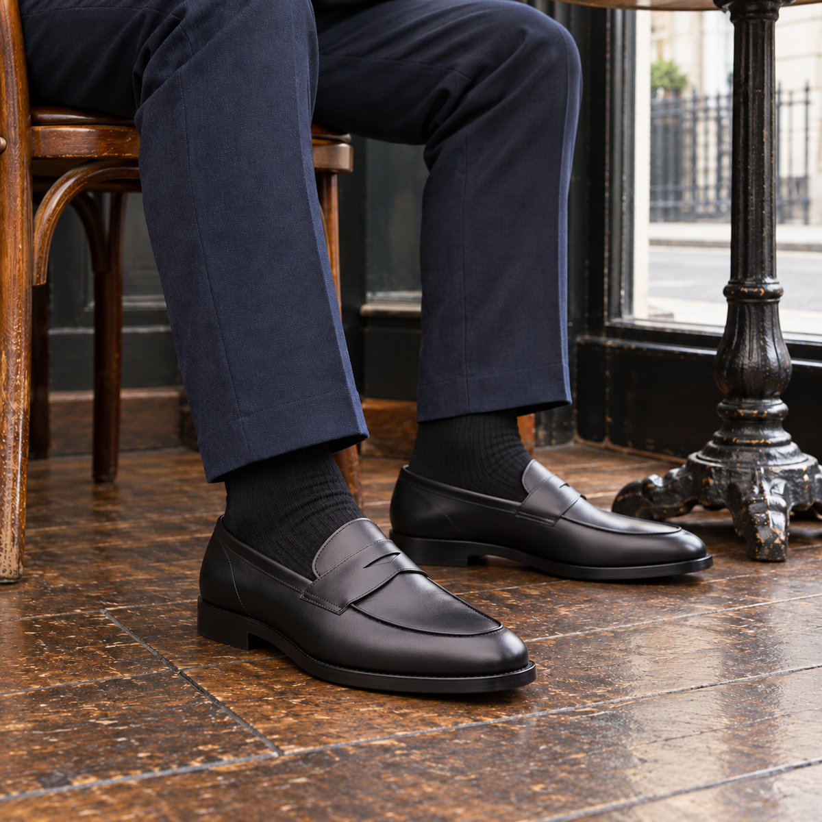 ASHFORD black calf leather penny loafers worn with navy trousers in a cafe
