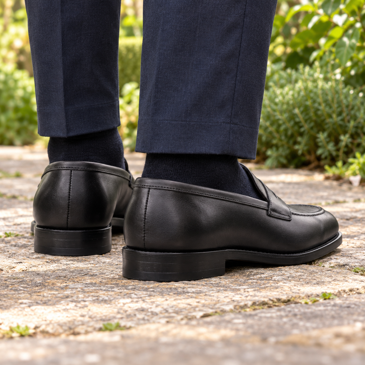 BURLINGTON black calf leather penny loafers — rear view showing heels and stitching in a garden